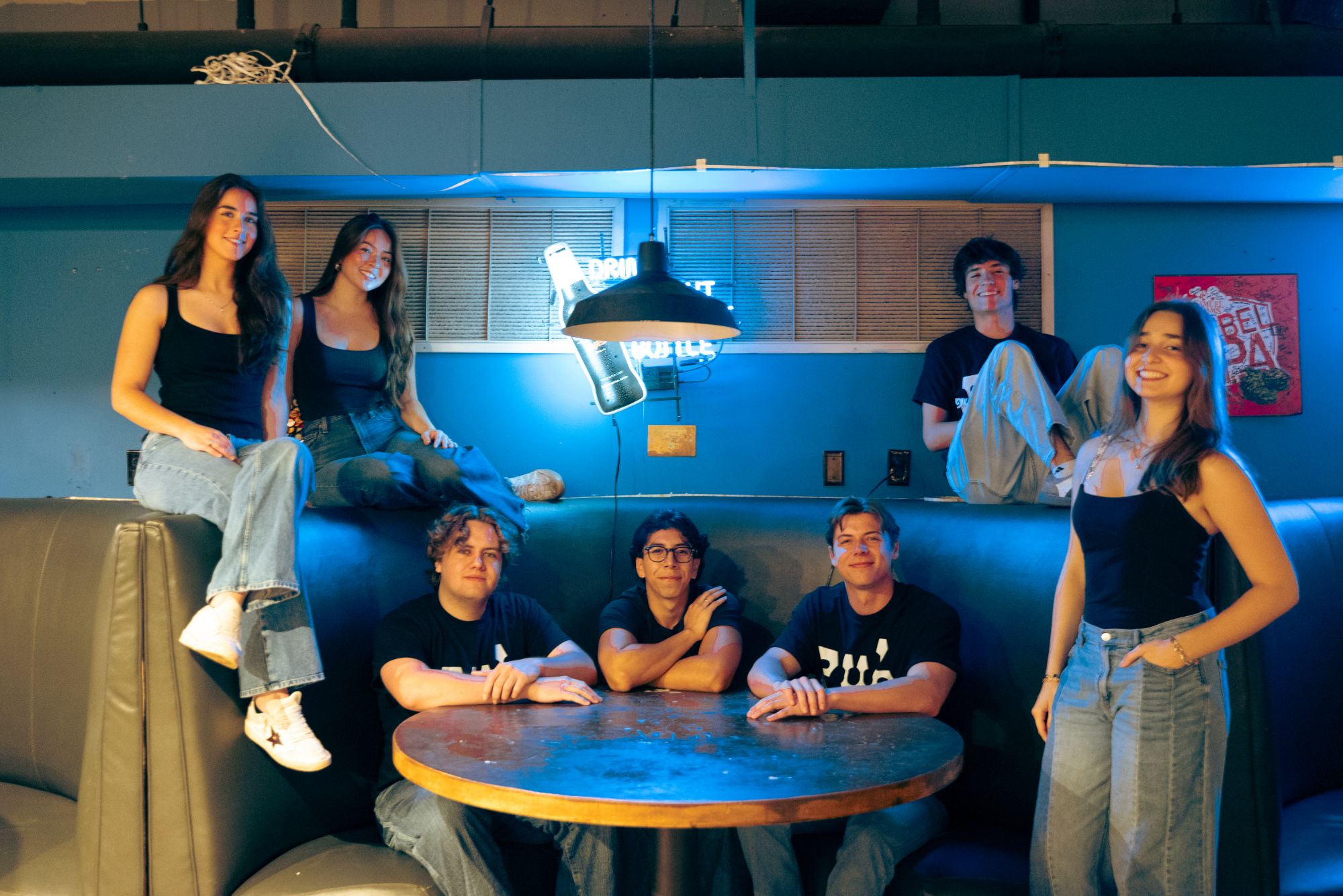 the pub team hanging out together in a blue-lit booth